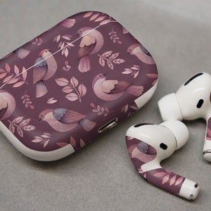 May include: A white wireless charging case with a purple floral pattern featuring birds. The case is designed for Apple AirPods Pro.