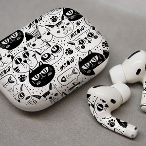 May include: White wireless earbuds with a black and white cat print design. The case is also decorated with a cat print design and the word "MEOW".