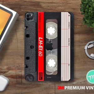 Op de afbeelding: Een zwart-witte cassetteband telefoonhoes met een rood label waarop "STEREOCASSETTE LH-EI 60 HIGH QUALITY" staat. De hoes heeft een 3M Premium Vinyl label.
