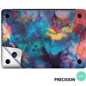 Könnte beinhalten: Eine Laptop-Haut mit einem farbenfrohen abstrakten Design in Blautönen, Lila, Gelb und Orange. Das Design ähnelt einem wirbelnden Nebel oder einer Galaxie.