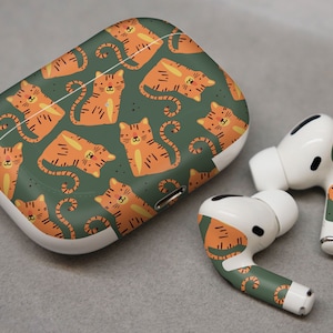 May include: A white wireless charging case with a green and orange tiger print design. The case is for Apple AirPods Pro. The case comes with two matching earbud covers.
