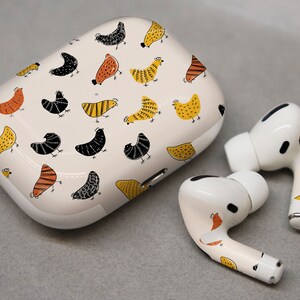 May include: White wireless earbuds with a chicken pattern on the case and earbuds. The case is white with a black and yellow chicken pattern. The earbuds are white with a black and yellow chicken pattern on the stem.