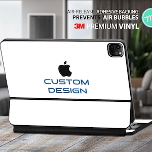 Peut inclure: iPad blanc avec une bordure noire et un logo Apple noir. Le texte "CUSTOM DESIGN" est en lettres bleues sous le logo. L'iPad est sur une surface en bois.