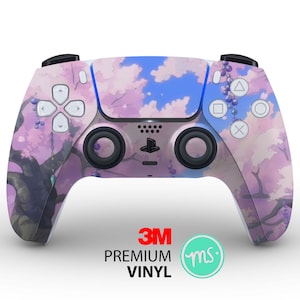 Op de afbeelding: Een roze en blauwe PlayStation 5-controller met een kersenbloesemboomontwerp. De controller heeft een 3M-logo en de tekst "PREMIUM VINYL".