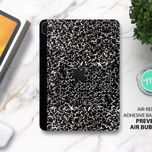 May include: Black and white speckled iPad skin with an air-release adhesive backing that prevents air bubbles. The skin has a textured, notebook-like design.