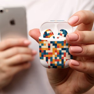 May include: A white wireless charging case for earbuds with a colorful geometric pattern in shades of blue, red, yellow, and white.