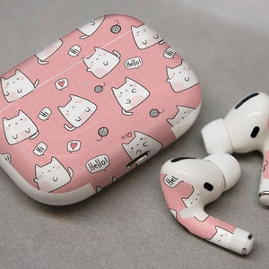 May include: Pink wireless earbuds with a cat print design. The case is also pink with a cat print design and says "Hello!" on it.
