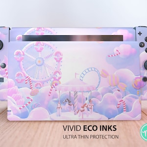 May include: A Nintendo Switch console with a custom skin featuring a whimsical carnival scene. The design includes a Ferris wheel, carousel, and candy elements in pastel pinks, purples, and blues. The text "VIVID ECO INKS ULTRA THIN PROTECTION" is visible.