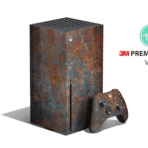 May include: A gaming console and controller skin set with a rusted metal design. The console is a rectangular tower with a textured surface, and the controller has matching colors. The text "3M PREMIUM VINYL" is visible.
