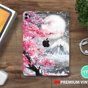 May include: A phone case with a pink and white floral design featuring a mountain and a moon. The case has a 3M Premium Vinyl label.