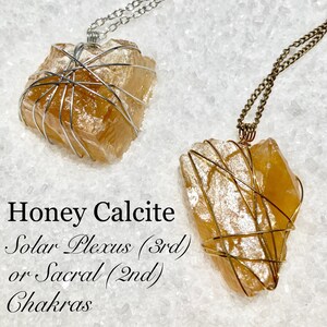 May include: Two honey calcite crystal pendants wrapped in wire. The pendant on the left is on a silver chain and the pendant on the right is on a gold chain. The text "Honey Calcite Solar Plexus (3rd) or Sacral (2nd) Chakras" is written below the pendants.