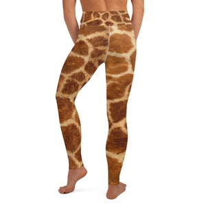 May include: Brown and tan giraffe print leggings. The leggings feature a high waist and a realistic giraffe pattern. The fabric appears to be soft and stretchy, suitable for yoga or other activities. The leggings are shown from the back.