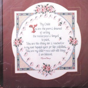May include: A Bucilla counted cross-stitch kit featuring a white fabric with a poem about a child printed in pink and blue. The poem reads "My Child, You are the poem I dreamed of writing, the masterpiece I longed to paint. You are the firing star I reached for in my ever tempest quest for happiness, you are my child now with all things, I am blessed." The kit is packaged in a clear plastic bag with a white and blue label that says "My Child" and "40733".