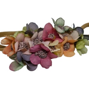 Könnte beinhalten: Ein braunes Gummiband mit einem Büschel bunter Stoffblumen. Die Blumen sind in den Farben Rosa, Orange, Grün und Lila.