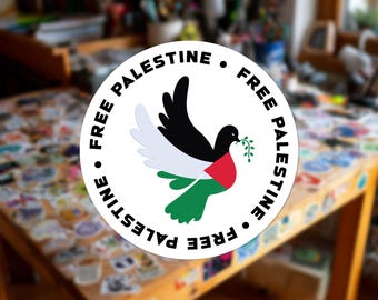 Può includere: Un adesivo circolare raffigurante una colomba stilizzata in volo, colorata con il nero, il bianco, il verde e il rosso della bandiera palestinese. La colomba tiene un piccolo ramoscello d'ulivo verde nel becco. Il testo "FREE PALESTINE" è nero.