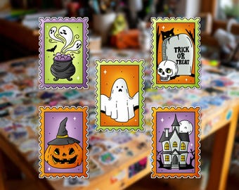Può includere: Cinque adesivi rettangolari a tema Halloween con bordi seghettati. I disegni includono un calderone viola con fantasmi, un fantasma arancione, una lapide con un teschio e il testo TRICK OR TREAT, una zucca e una casa stregata con luna piena.