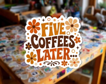 Può includere: Un adesivo fustellato con il testo FIVE COFFEES LATER... in un carattere audace di ispirazione retrò. Il design è decorato con varie illustrazioni di fiori color arancione, marrone e crema, piccoli cerchi e stelle su uno sfondo bianco.