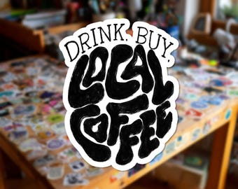 Può includere: Un adesivo fustellato con un testo nero, audace e scritto a mano che recita "DRINK. BUY. LOCAL COFFEE.". Le lettere hanno un aspetto ondulato e distorto con un bordo bianco spesso che circonda l'intero design, creando una grafica ad alto contrasto.