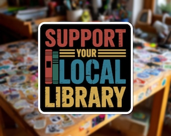 Può includere: Un adesivo quadrato con sfondo nero che riporta il testo SUPPORT YOUR LOCAL LIBRARY in un carattere usurato multicolore. Il design include due icone di libri verticali in rosso e verde, con linee orizzontali gialle che fiancheggiano la parola YOUR.