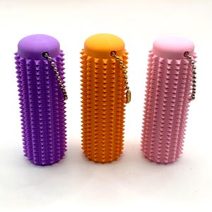Peut inclure: Trois rouleaux de massage colorés, violets, oranges et roses. Chaque rouleau a une forme cylindrique avec une surface à pointes et une petite chaîne. Les rouleaux sont conçus pour le soulagement musculaire. Mesure environ 10 cm de long.