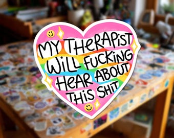 Può includere: Un adesivo a forma di cuore con uno sfondo color arcobaleno e un bordo bianco. Il testo MY THERAPIST WILL FUCKING HEAR ABOUT THIS SHIT è scritto in lettere nere. Il design include due faccine sorridenti e quattro icone a stella gialle.