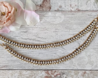 May include: A pair of gold anklets with white beads and clear rhinestones.