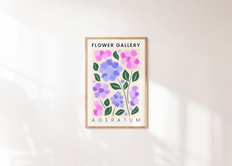May include: A framed print with the title "FLOWER GALLERY" and the name of the flower "AGERATUM" in black text. The print features a stylized illustration of purple and pink flowers with green leaves on a cream background.