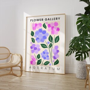 May include: A poster with the title "FLOWER GALLERY" and the text "AGERATUM" at the bottom. The poster features a stylized illustration of purple and pink flowers with green stems on a cream background.