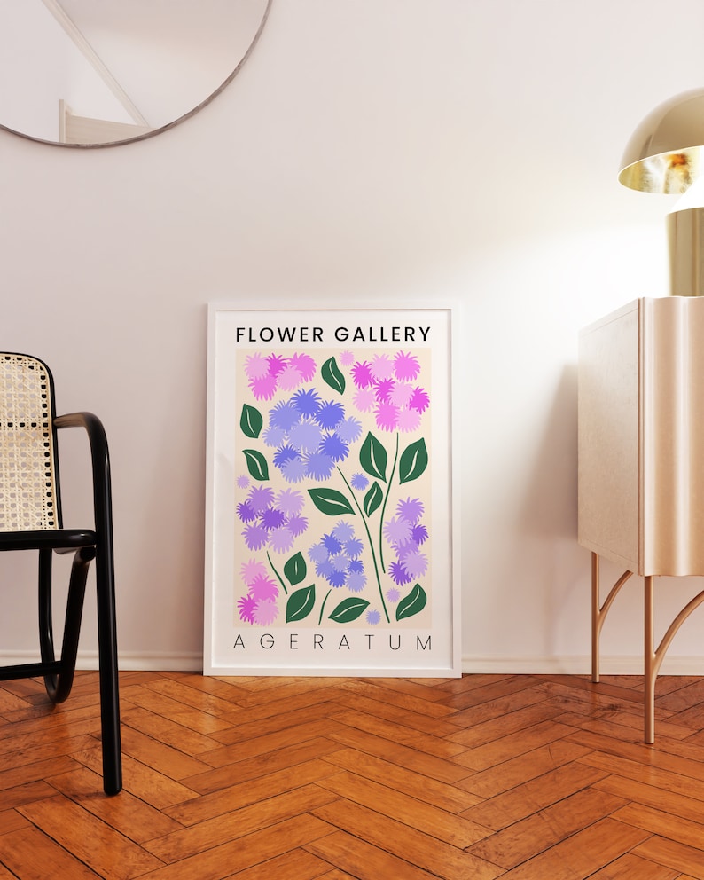 May include: A framed print with a cream background featuring a stylized illustration of purple and pink flowers with green leaves. The text "FLOWER GALLERY" and "AGERATUM" is printed in black at the top and bottom of the print.