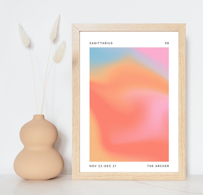 Może przedstawiać: Wydruk w ramie z gradientowym tłem w odcieniach r&oacute;żowego, pomarańczowego i niebieskiego. Tekst "SAGITTARIUS 09" znajduje się u g&oacute;ry wydruku, a tekst "NOV 22-DEC 21 THE ARCHER" u dołu.