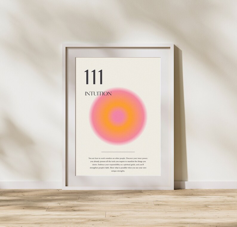 May include: A white framed poster with the number 111 and the word "INTUITION" in black text. A pink and orange circle with a smaller orange circle in the center is in the middle of the poster. The text below the circle reads: "You are here to work wonders on other people. Discover your inner power, you already possess all the tools you require to manifest the things you desire. Embrace your responsibility as a spiritual guide, and you'll strengthen people's faith. Show what is possible when you use your own unique strengths."