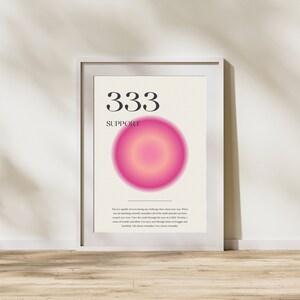 May include: A white framed poster with a pink and yellow gradient circle in the center. The number 333 and the word "SUPPORT" are printed in black at the top of the poster. The text below the circle reads: "You are capable of overcoming any challenge that comes your way. When you are doubting yourself, remember all of the small miracles you have created over time. View the world through the eyes of a child. Develop a sense of wonder and allow it to carry you through times of struggle and hardship. Life always triumphs. Love always triumphs."