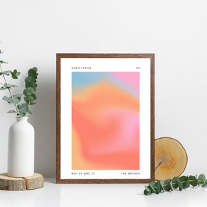 Może przedstawiać: Wydruk w ramie z gradientowym tłem w odcieniach r&oacute;żowego, pomarańczowego i niebieskiego. Tekst "Sagittarius" znajduje się u g&oacute;ry wydruku, wraz z liczbą "09". Tekst "Nov 22-Dec 21" i "The Archer" znajduje się u dołu wydruku.