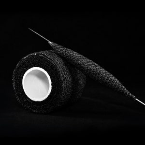 May include: A roll of black athletic tape with a white core, and a black and silver needle.