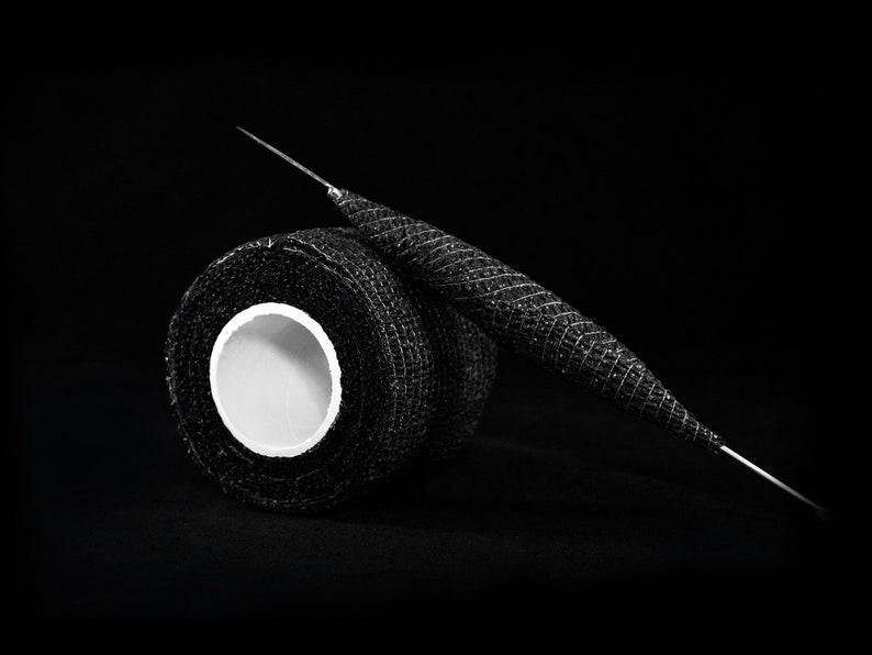 May include: A roll of black athletic tape with a white core, and a black and silver needle.