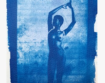 May include: A cyanotype photograph of a person posing with their arms raised above their head. The background is a textured blue surface.