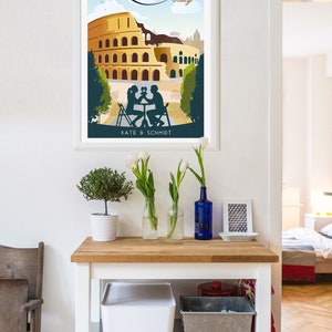 May include: A white framed poster with a vintage travel illustration of the Colosseum in Rome, Italy. The poster features a couple sitting at a table with a glass of wine. The text on the poster reads "ROME Italy" and "KATE & SCHMIDT".