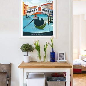 Puede incluir: Un p&oacute;ster enmarcado con una ilustraci&oacute;n colorida de una g&oacute;ndola en un canal de Venecia, Italia. El p&oacute;ster tiene el texto "Venecia, Italia" y "Kate & Schmidt" en la parte inferior.