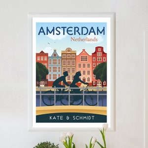May include: A vintage travel poster design featuring a couple riding bicycles on a bridge in Amsterdam, Netherlands. The poster has a blue sky with white clouds, colorful buildings, and the text "AMSTERDAM Netherlands" and "KATE & SCHMIDT".