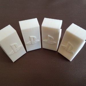 May include: Four white plastic game console controller stands with the PlayStation logo embossed on each.