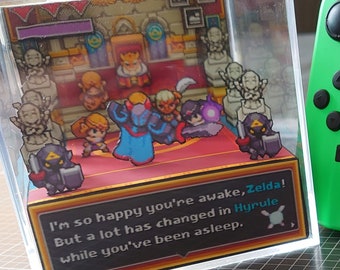 May include: A clear acrylic box with a 3D papercraft scene inside depicting characters from the Legend of Zelda video game series. The box is sitting on a black and white grid surface next to a green Nintendo Switch console. The console's screen shows the Animal Crossing: New Horizons game icon. The text on the box reads "I'm so happy you're awake, Zelda! But a lot has changed in Hyrule while you've been asleep."