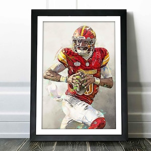 May include: A watercolor-style illustration of a football player in a red and yellow uniform with the word "Commanders" on the jersey. The player is holding a football and running with the ball.