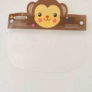 May include: A clear plastic face shield with a brown monkey design. The shield has a warning label that says "Warning: can only be used as Mask prevent to the liquid from overflowing." The shield also has instructions that say "Use Instructions: Please remove the outer plastic Protective film before using."