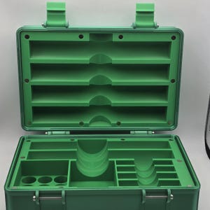 Pu&ograve; includere: Cassetta degli attrezzi in plastica verde aperta con pi&ugrave; scomparti e ripiani. La met&agrave; superiore della cassetta degli attrezzi &egrave; aperta, rivelando diversi ripiani orizzontali. La met&agrave; inferiore ha varie sezioni di stoccaggio.