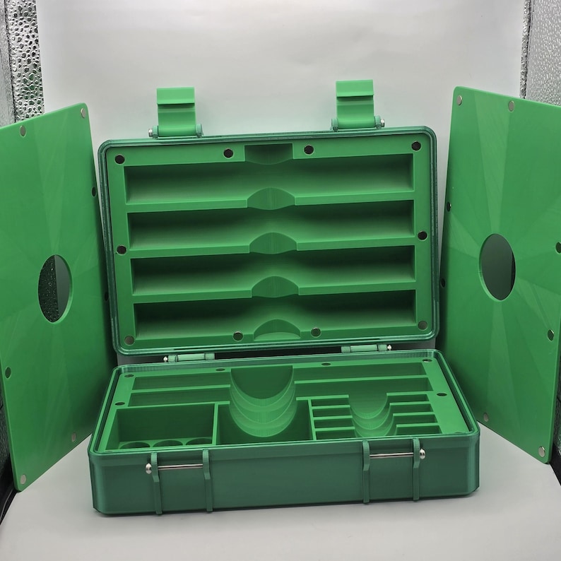 Pu&ograve; includere: Cassetta degli attrezzi in plastica verde aperta con pi&ugrave; scomparti e una maniglia. La cassetta degli attrezzi &egrave; aperta, rivelando varie sezioni di stoccaggio e una serie di ripiani. Due pannelli verdi sono su entrambi i lati.