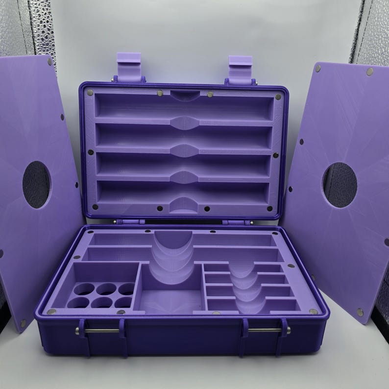 Pu&ograve; includere: Una cassetta degli attrezzi viola, aperta, con pi&ugrave; scomparti e un coperchio incernierato. L'interno presenta varie fessure e supporti per organizzare utensili o forniture. Il coperchio &egrave; staccato, rivelando l'interno. La cassetta &egrave; realizzata in materiale resistente.