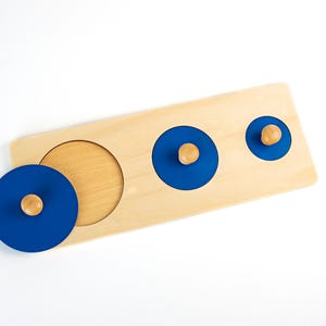 May include: A wooden puzzle with three blue circles with wooden knobs. The circles are different sizes and fit into the corresponding cutouts on the board.