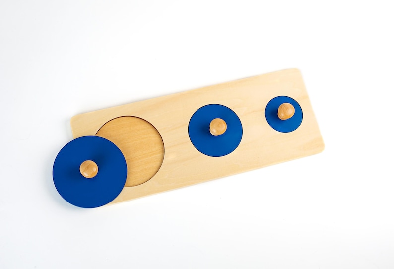 May include: A wooden puzzle with three blue circles with wooden knobs. The circles are different sizes and fit into the corresponding cutouts on the board.
