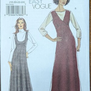 May include: Vogue pattern V8410 featuring two dress designs. One dress is a long, dark gray plaid jumper over a white turtleneck. The other is a long, burgundy wrap dress with a white blouse underneath.