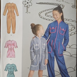 May include: Simplicity sewing pattern R11705 for children's jumpsuits. The pattern includes three jumpsuit designs: a tan jumpsuit, a pink and white checkered jumpsuit, and a teal jumpsuit. The pattern is designed for sizes 3-6.
